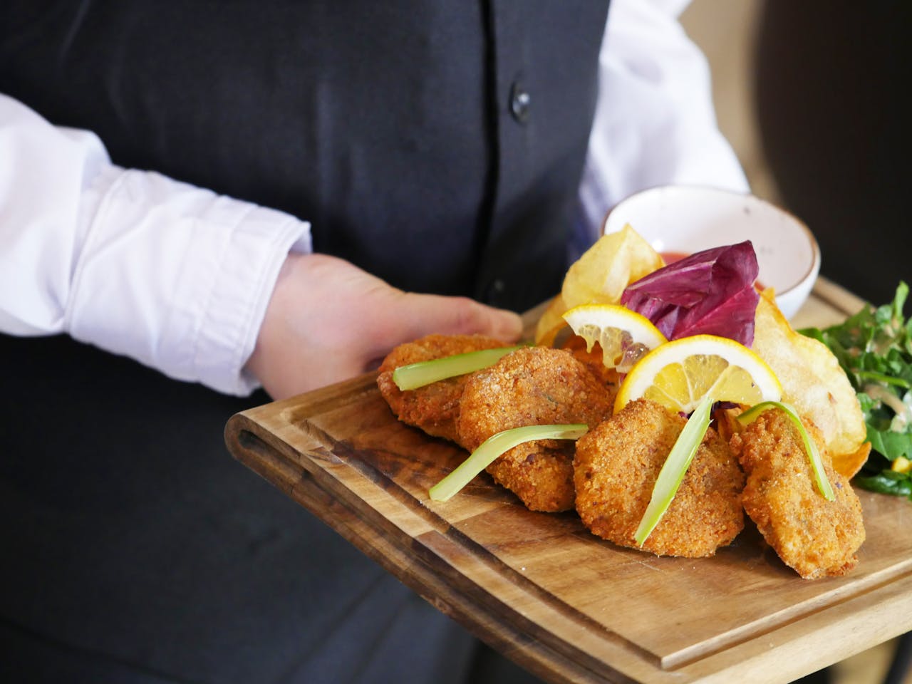 Close-up of a delicious meal with crispy nuggets and chips served on a wooden board.